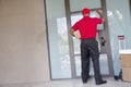 Rear view of a delivery man with packages knocking at door