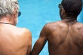 Rear view of diverse senior adults sitting by the pool enjoying