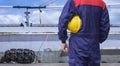 Engineer in blue mechanic jumpsuit holding yellow safety helmet before working on oil tanker in shipyard area Royalty Free Stock Photo