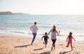 Rear View Of Family On Beach Running Across Sand Towards Sea Royalty Free Stock Photo