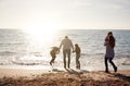 Rear View Of Family Jumping Over Waves Looking Out To Sea Silhouetted Against Sun Royalty Free Stock Photo