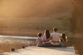 Rear View Of Family Standing On Wooden Jetty By Lake