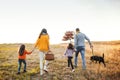 A rear view of family with two small children and a dog on a walk in autumn nature.