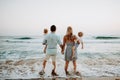 A rear view of family with two toddler children standing on beach on summer holiday. Royalty Free Stock Photo