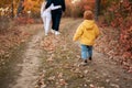 Rear view of family walking along autumn woodland path together. Mother and father hug, son go alone Royalty Free Stock Photo