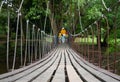 Rear view of family walking on suspension wooden bridge with nets or rope handrails in the park