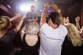 Rear view of fans enjoying with arms raised at nighclub