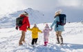 Pohľad zozadu na otca a mamu s dvoma malými deťmi v zimnej prírode, chôdzu v snehu.