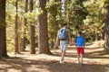 Rear View Of Father And Son On Hiking Adventure Through Forest