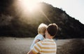 Rear view of father with a toddler boy on beach on summer holiday at sunset. Royalty Free Stock Photo