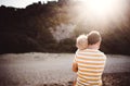 Rear view of father with a toddler boy standing on beach on summer holiday at sunset. Royalty Free Stock Photo