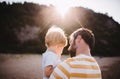 Rear view of father with a toddler boy standing on beach on summer holiday at sunset. Royalty Free Stock Photo