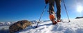 Rear view of the feet of a mountaineer walking on snow with poles in a high mountain landscape. Adventure sports concept Royalty Free Stock Photo