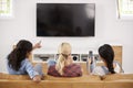 Rear View Of Female Friends Sitting On Sofa Watching Television