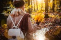 Rear view of female holding bouquet of yellow autumn maple leaves in her gloved hands. Ground covered with orange leaves Royalty Free Stock Photo