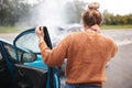 Rear View Of Female Motorist With Head Injury Getting Out Of Car After Crash