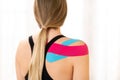Rear view of a female patiet with kinesio tape on her shoulder. Kinesiology, physical therapy, rehabilitation concept. Royalty Free Stock Photo