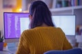 Rear view of female programmer working from home using multiple monitors to write code Royalty Free Stock Photo