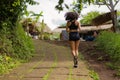 Rear view female runner training on countryside road - young attractive and fit jogger woman doing running workout outdoors at Royalty Free Stock Photo