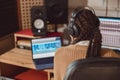Female sound engineer musician with headphones sitting at desk with laptop while recording new song in the music studio