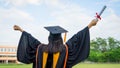 Rear view of a female university graduate stands and holds degree certificate to celebrate in the  graduation ceremony with clear Royalty Free Stock Photo