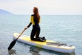Rear view on fit redhead woman standing paddling away on stand up paddleboarding at sea