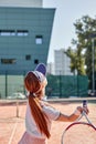 Rear view on forceful fit woman playing tennis in outdoor court, hitting ball, training Royalty Free Stock Photo