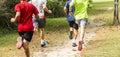 Rear view of four runners running fast in a park