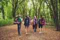 Rear view of four tourists walking in the forest, holding map, t