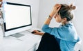 Rear view of a freelacer businesswoman using desktop computer in the office. Pretty young blonde woman sit indoors at home working Royalty Free Stock Photo