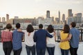 Rear View Of Friends Gathered On Rooftop Terrace Looking Out Over City Skyline Royalty Free Stock Photo