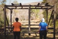 Rear view of friends looking at monkey bar during obstacle course Royalty Free Stock Photo
