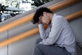 Rear view of frustrated stressed young Asian business man sitting staircase of office and feeling tried or exhausted. Royalty Free Stock Photo