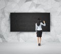 Rear view of full-length woman who is writing something on the empty black board. Royalty Free Stock Photo