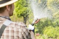 Rear view of gardener watering plants at garden