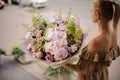 Rear view of girl who holds large bouquet with orchids and other flowers