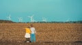 Rear view of girl and boy in front of the wind turbines farm. concept of sustainable resources and renewable energy Royalty Free Stock Photo