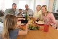 Girl clicking photo of her family with mobile phone on dining table Royalty Free Stock Photo