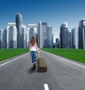 Rear view of a girl with a suitcase entering the city. Royalty Free Stock Photo