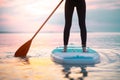 Rear view of girl surfer paddling on surfboard on the lake at sunrise, lowsection. Royalty Free Stock Photo