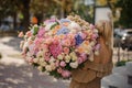 Rear view of girl who holds huge bouquet of different flowers