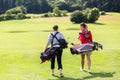 Rear view of golfing couple walking on golf green Royalty Free Stock Photo