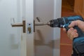 Rear view of a good looking man working as handyman and fixing a door lock