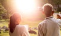 Rear view of granddaughter and grandfather drinking hot coffee outdoor and enjoying landscape during holiday on the mountain with Royalty Free Stock Photo