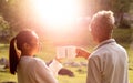 Rear view of granddaughter and grandfather drinking hot coffee outdoor and enjoying landscape during holiday on the mountain with Royalty Free Stock Photo