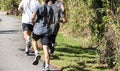 Rear view of group of boys running together on a tar path in a park Royalty Free Stock Photo