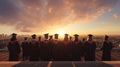 Rear view of a group of graduates standing outdoors, at sky sunset