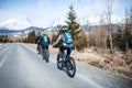 Rear view of group of mountain bikers riding on road outdoors in winter. Royalty Free Stock Photo