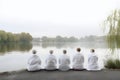 rear view of group of senior women doing yoga exercises in front of summer morning lake, neural network generated