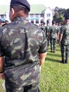 Rear view, a group of uniformed soldiers standing in line outdoors on select focus lawn.